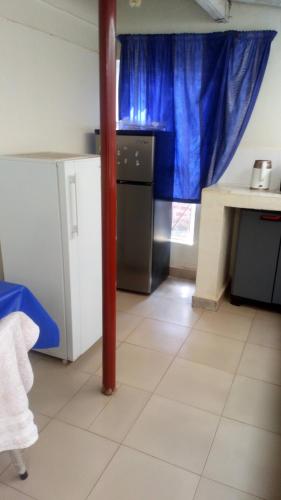 a kitchen with a refrigerator and a table and a window at Knowledge For Change House in Fort Portal