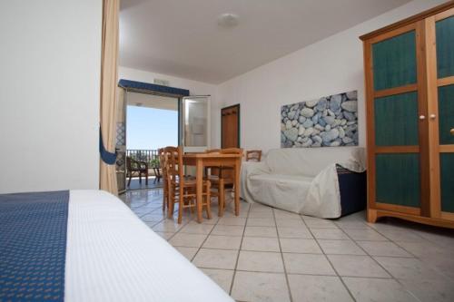 een slaapkamer met een bed, een tafel en stoelen bij Baraka Apartments in Scoglitti