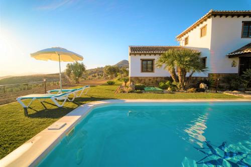 une villa avec une piscine et une maison dans l'établissement Casa Rural Los Menhires, à Malaga