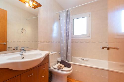 baño con lavabo y aseo y ventana en Villa la Roca en Sant Antoni de Calonge