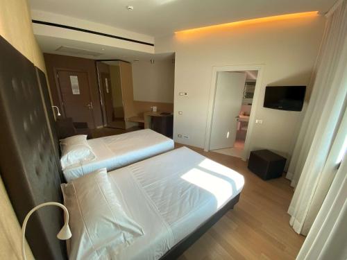 a hotel room with two beds and a television at Devero Hotel & Spa, BW Signature Collection in Cavenago di Brianza