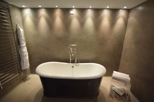 a bath tub in a bathroom with a wall at Devero Hotel & Spa, BW Signature Collection in Cavenago di Brianza