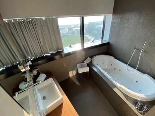 a bathroom with a tub and a sink and a window at Devero Hotel & Spa, BW Signature Collection in Cavenago di Brianza
