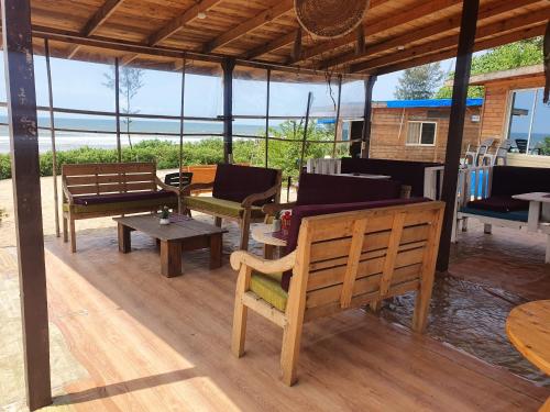 einen Pavillon mit Bänken und Tischen auf einem Holzboden in der Unterkunft Love Temple Beach Resort in Arambol