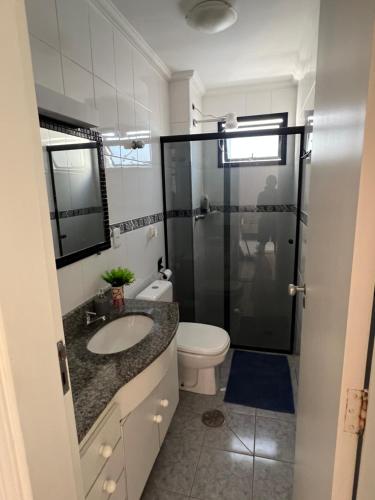 a bathroom with a toilet and a sink and a shower at Edifício Gorja in Praia Grande