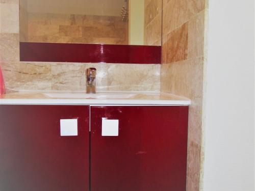 La salle de bains est pourvue d'un lavabo et d'une armoire rouge. dans l'établissement Studio cosy avec balcon face à la plage - Les Sables-d'Olonne - FR-1-197-275, à Les Sables-dʼOlonne