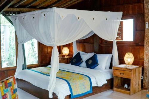 a bedroom with a canopy bed with white curtains at Sentana Villa Ubud in Ubud