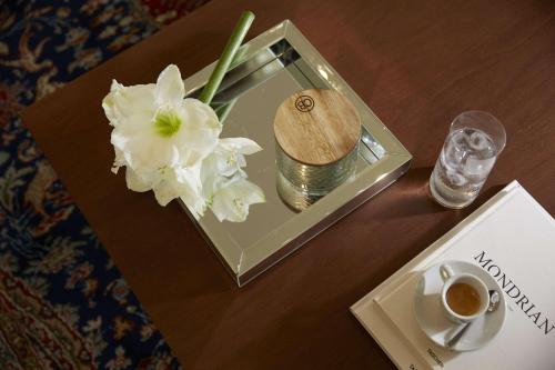 a table with a glass box with flowers and a cup of coffee at Mon Repos Palace - Adults Only in Corfu