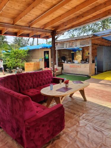 een woonkamer met een rode bank en een tafel bij Love Temple Beach Resort in Arambol