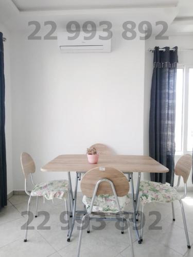 a wooden table and chairs with a price sign on the wall at second position beach Dar Allouche Klibia Rfi Rdc in Hanshīr Qaşr Ghallāb