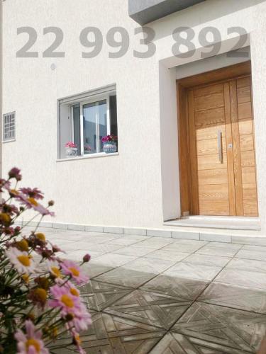 a building with a door and a window and flowers at second position beach Dar Allouche Klibia Rfi Rdc in Hanshīr Qaşr Ghallāb