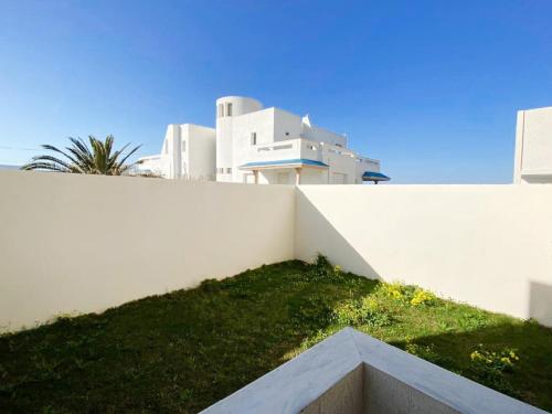 a white wall with a grassy yard next to a building at S2 in second position beach Dar Allouche Kelibia in Hennchir Ksar Rhaleb