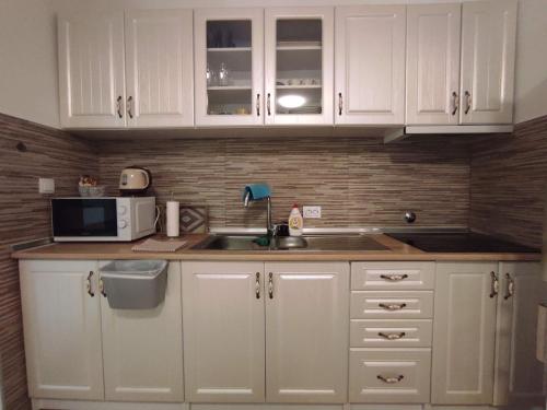 a kitchen with white cabinets and a sink and a microwave at Apartman Olga in Trebinje