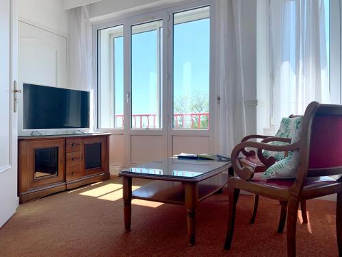 a living room with a table and a chair and a tv at Abalys Hotel in Brest