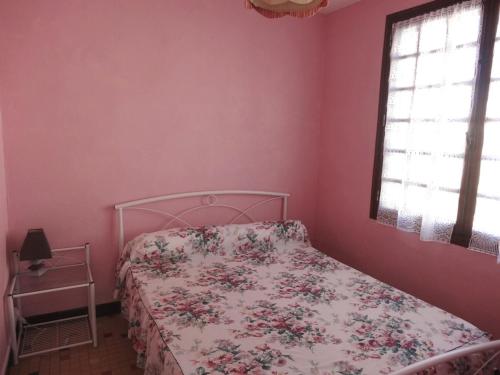 1 dormitorio con paredes rosas y 1 cama con colcha de flores en Maison L'Aiguillon-sur-Mer, 4 pièces, 5 personnes - FR-1-476-2, en LʼAiguillon-sur-Mer