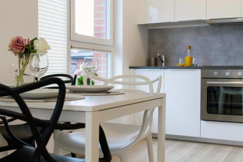 kuchnia z białym stołem z krzesłami, stołem i stołem w obiekcie Nowa Grobla Estate Apartment near Starówka by Renters w Gdańsku
