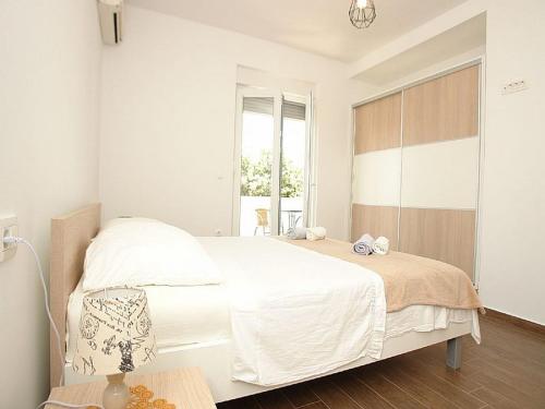 a white bedroom with a large bed and a window at Pansion Jurko in Pag