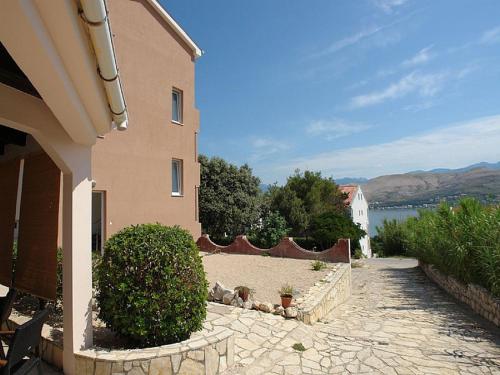 a house with a stone walkway next to a building at Pansion Jurko in Pag