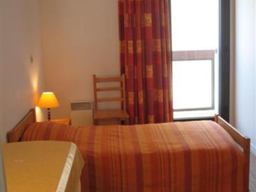 une chambre avec un lit, une chaise et une fenêtre dans l'établissement La Rochelle: Appt 3 pièces, 6 pers, piscine, parking, proche plage - FR-1-551-19, à La Rochelle