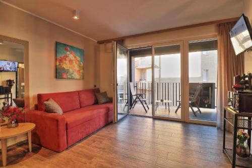 ein Wohnzimmer mit einem roten Sofa und einem Balkon in der Unterkunft Villa Hedy Luxury Apartments - Happy Rentals in Meran