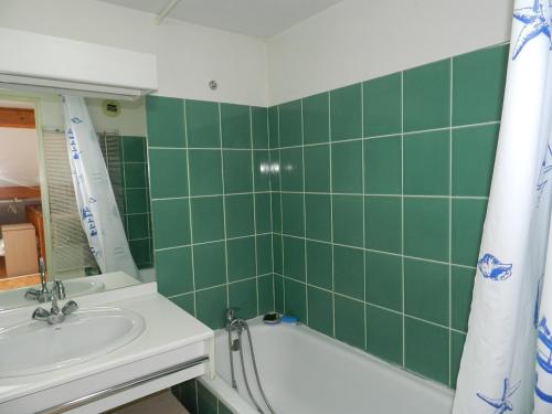La salle de bains carrelée de couleur verte est pourvue d'un lavabo et d'une baignoire. dans l'établissement Charmant T2 avec piscine aux Minimes, proche plage - La Rochelle - FR-1-551-48, à La Rochelle