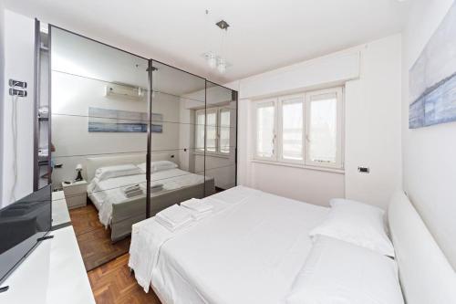 a white bedroom with two beds and a mirror at La casa di Pablo in Cinisello Balsamo