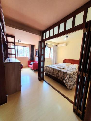 a bedroom with a bed and a living room at Flat Wall Street in Caxias do Sul