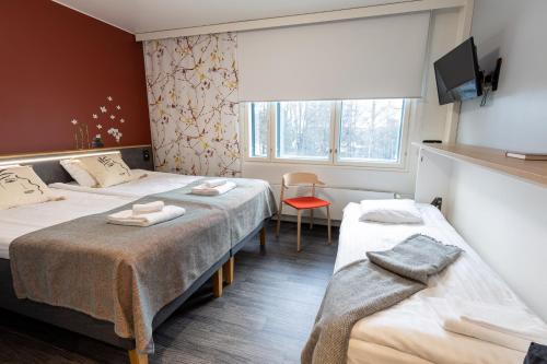 a hotel room with two beds and a window at Hotel Linnasmäki in Turku