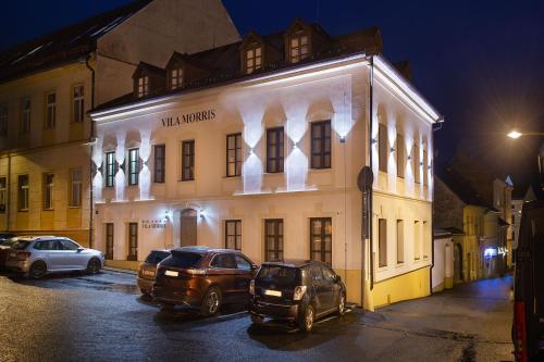 dwa samochody zaparkowane w nocy przed budynkiem w obiekcie Hotel Morris Premium Collection w mieście Česká Lípa