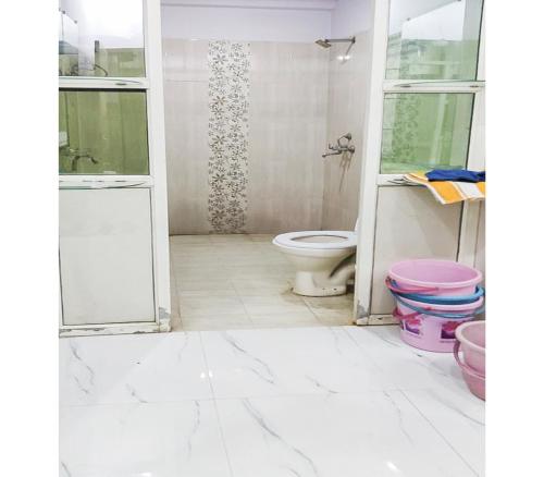 a white bathroom with a toilet and a shower at Toran Guest House By WB Inn in Agra
