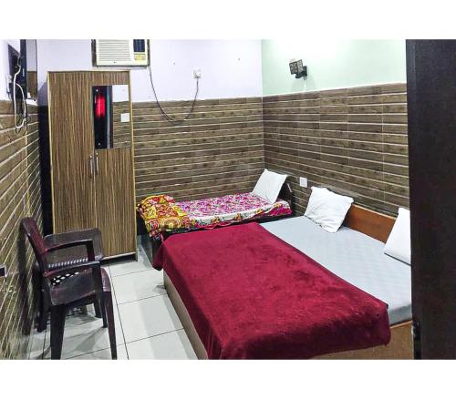 a room with two beds and a chair in it at Toran Guest House By WB Inn in Agra