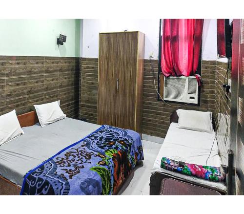 a bedroom with two beds and a window with a fan at Toran Guest House By WB Inn in Agra