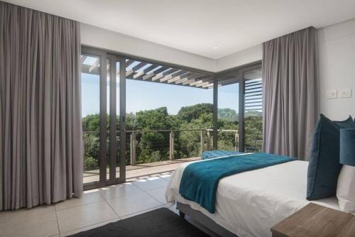 a bedroom with a bed and a large window at Stylish 19 Ocean's Edge 4 Bedroom Home, Zimbali in Ballito