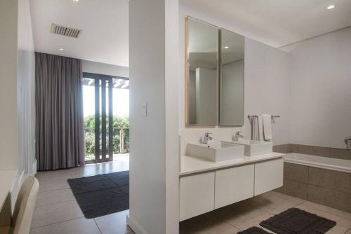 a white bathroom with a sink and a mirror at Stylish 19 Ocean's Edge 4 Bedroom Home, Zimbali in Ballito