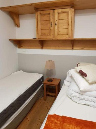 um quarto com 2 camas e uma mesa com um candeeiro em SCI Maha em Les Carroz d'Arâches