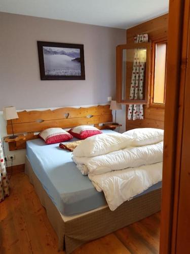 um quarto com 2 camas com lençóis brancos e almofadas vermelhas em SCI Maha em Les Carroz d'Arâches