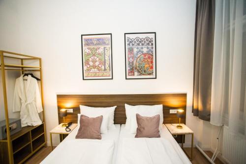una camera da letto con un grande letto bianco con tre immagini sul muro di Pension Central I Self Check In a Vienna