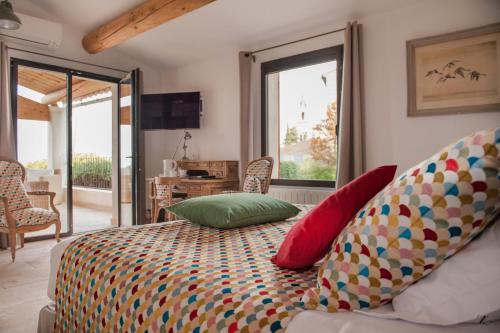 a bedroom with a bed with colorful pillows on it at Le Clos Du Buis in Bonnieux