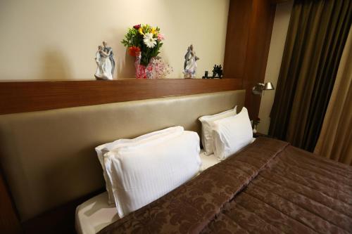 a bedroom with a bed with two pillows and a vase of flowers at SilverCloud Hotel and Banquets in Ahmedabad