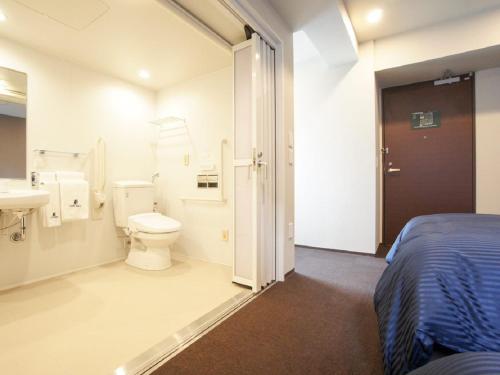 a bathroom with a bed and a toilet and a sink at HOTEL LiVEMAX Yokohama Motomachi Ekimae in Yokohama