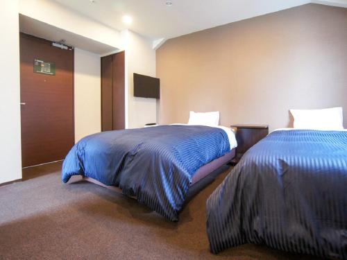 um quarto de hotel com duas camas com lençóis azuis em HOTEL LiVEMAX Yokohama Motomachi Ekimae em Yokohama