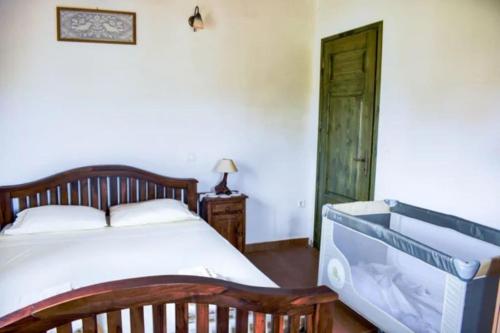 a bedroom with a white bed and a wooden door at Villa Andreas-Dimitris in Volimes