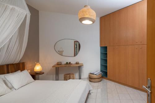 a bedroom with a white bed and a mirror at Escape In Blue in Stalida