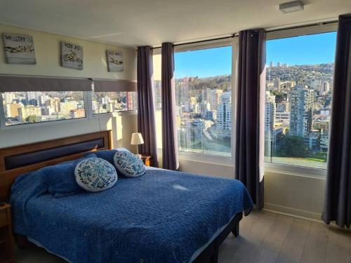 een slaapkamer met een blauw bed en grote ramen bij Hermoso departamento en Viña del Mar/Casino in Viña del Mar