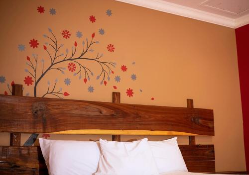 ein Schlafzimmer mit einem Bett mit einem Baumbild an der Wand in der Unterkunft MSC Hotel Otjiwarongo in Otjiwarongo