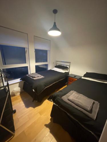 twee bedden in een kamer met twee ramen bij Duntocher village flat in Clydebank