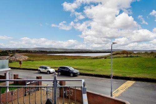 two cars parked in a parking lot next to a field at Heron House in Haverigg