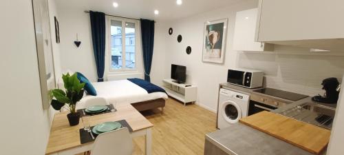 a hotel room with a bed and a kitchen with a sink at Garnavie - Centre ville - Les Halles in Lourdes