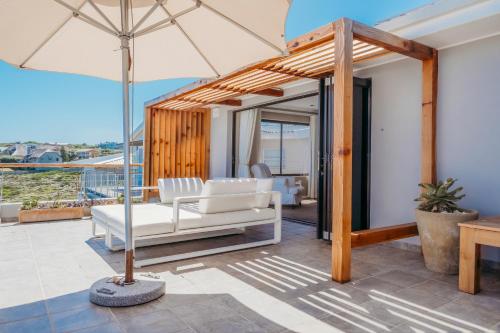 a patio with a white couch and an umbrella at Cliff Lodge in Gansbaai