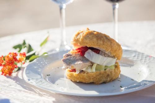 a sandwich on a plate on a table with wine glasses at Hotel Tugasa El Almendral in Setenil